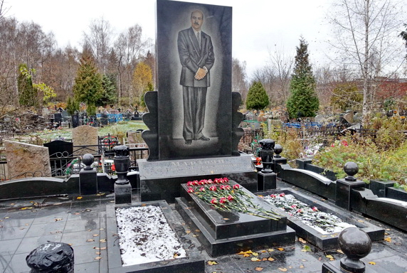 Высокое гранитное надгробье прямоугольной формы и два цветника
